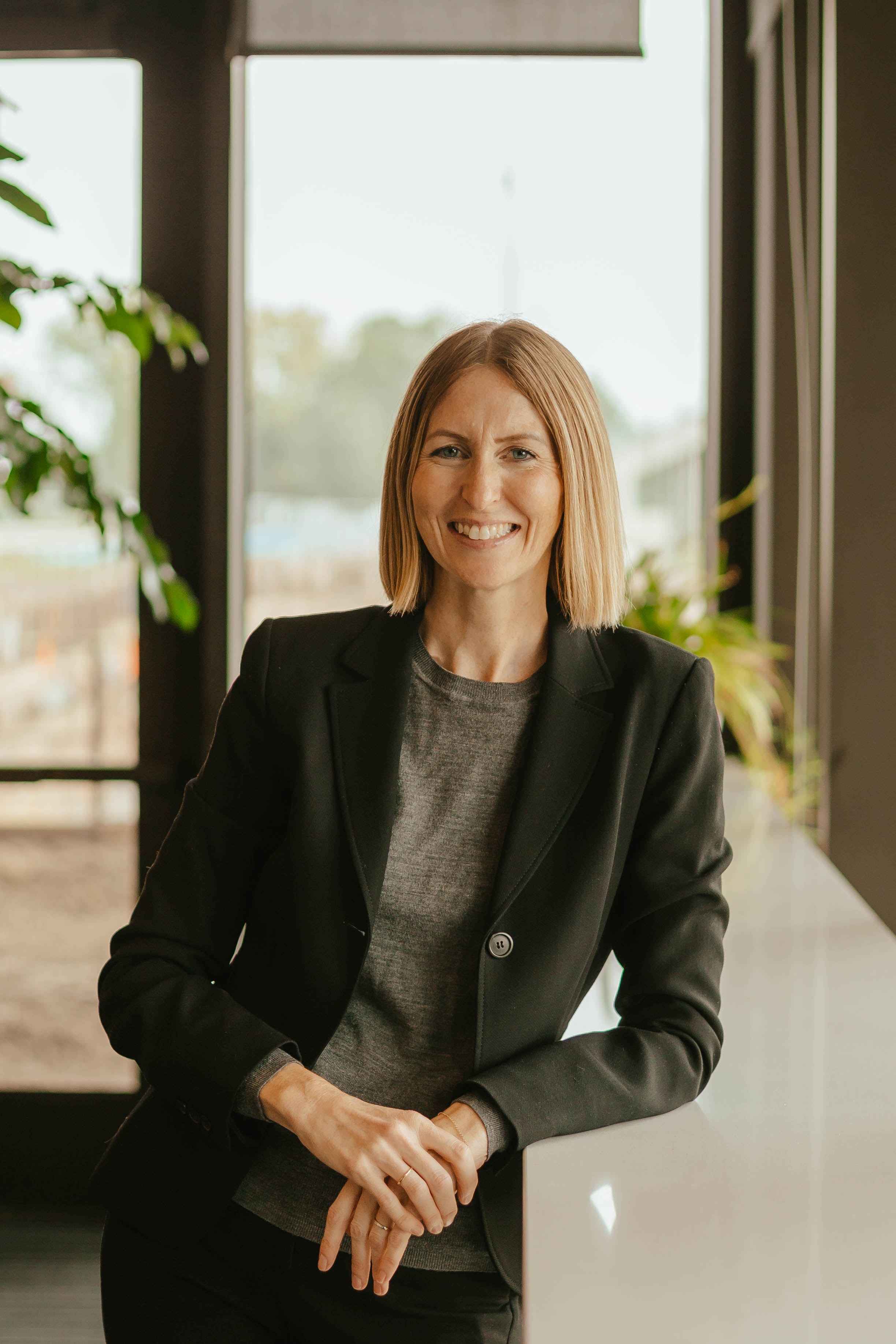 Picture of Lauren Finke leaning against a counter in a room with natural light from windows. 
