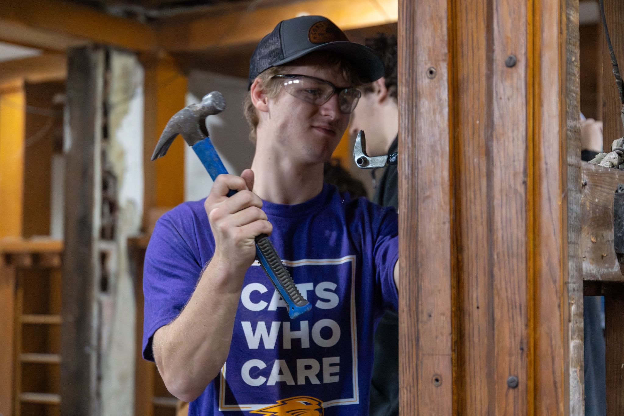 Student using hammer while wearing Cats Who Care shirt